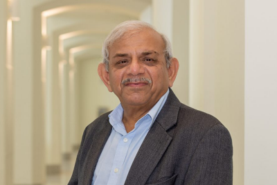 Patty Raun Portrait of Raman Kumar wearing a suit and standing in a hallway.